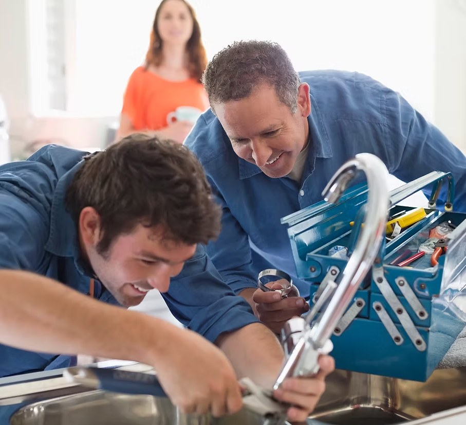 Two plumbers repairing a kitchen mixer tap